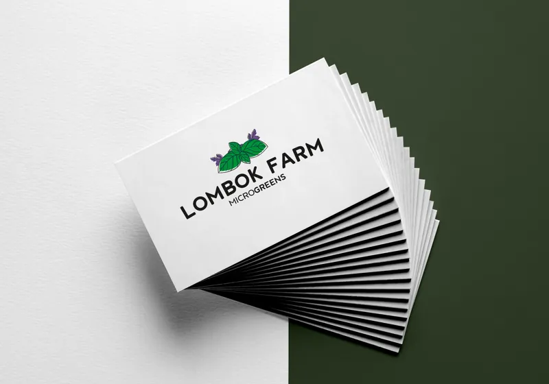 A fanned stack of white business cards with the Lombok Farm Microgreens logo in green and purple.